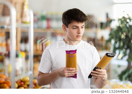 European guy looks at product and shop around, choose and buy spaghetti items in shop European guy looks at product and shop around, choose and buy spaghetti items in shop 132044048