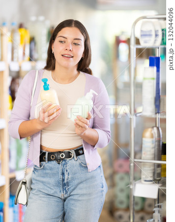 Young woman buyer chooses liquid soap in store Young woman buyer chooses liquid soap in store 132044096