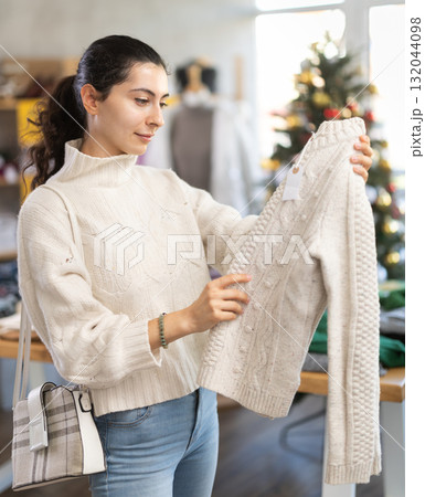 Armenian girl near showcase pick out and buying sweater, New Year eve Armenian girl near showcase pick out and buying sweater, New Year eve 132044098