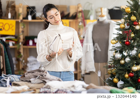 Happy young Armenian girl choosing handbag in clothing store 132044140