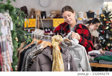 Young girl near showcase pick out and buying down jacket, New Year eve 132044279