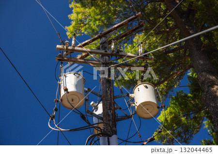 Wooden utility pole with power transformers and electrical cables against blue sky in the United States 132044465