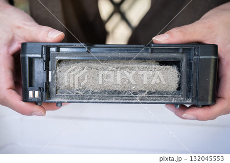 Woman holding a vacuum dust filter for cleaning it. 132045553