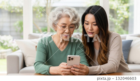 老人にスマホの操作方法を教える若い女性 132046603