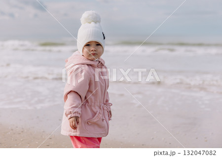 Cute child girl on ocean coastline. Winter holidays concept. Cute child girl on ocean coastline. Winter holidays concept. 132047082