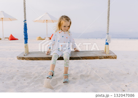 Little child girl on swings on tropical beach, enjoy childhood Little child girl on swings on tropical beach, enjoy childhood 132047086
