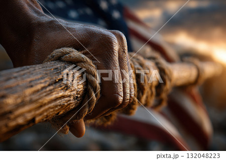 Hand gripping flagpole with fluttering flag in strong breeze 132048223