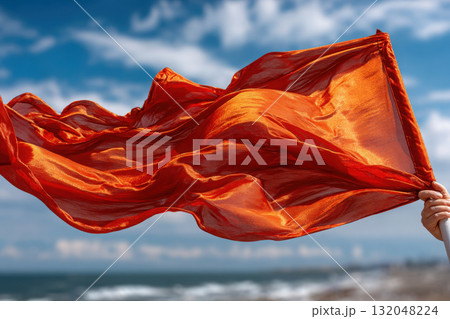 Hand gripping flagpole with vibrant flag fluttering in wind 132048224