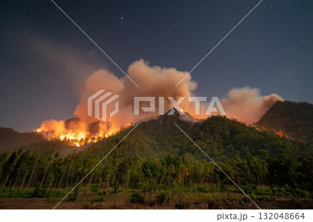 Wildfire spreads across mountains under night sky Wildfire spreads across mountains under night sky 132048664