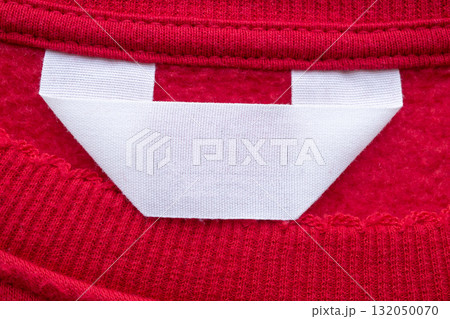 Blank white laundry care clothes label on red shirt fabric texture background Blank white laundry care clothes label on red shirt fabric texture background 132050070