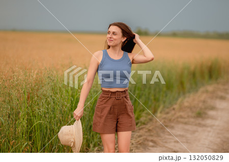 Woman enjoying a summer day on a rural path surrounded by golden fields Woman enjoying a summer day on a rural path surrounded by golden fields 132050829