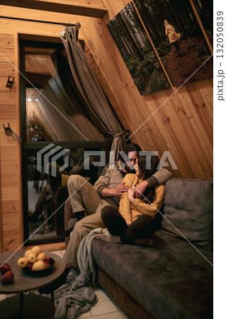 Cozy couple enjoys intimate moments in a wooden cabin setting at night Cozy couple enjoys intimate moments in a wooden cabin setting at night 132050839