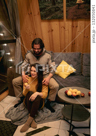 Couple enjoying cozy moments at home during a winter evening with snacks and warmth Couple enjoying cozy moments at home during a winter evening with snacks and warmth 132050841