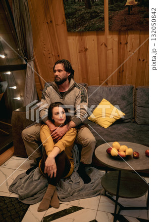 Couple relaxing together in a cozy cabin during evening hours Couple relaxing together in a cozy cabin during evening hours 132050842