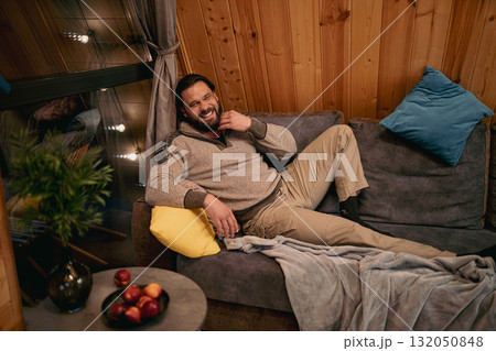 Relaxing man enjoys cozy indoor space with snacks and warm decor during evening at home 132050848