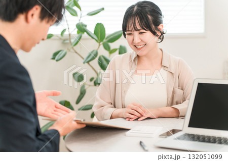 商談で電卓を使い金額を提示するビジネスマンと話を聞く女性客 132051099
