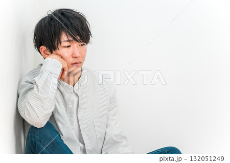 頬杖をつきながら俯いて落ち込んでいる若いアジア人男性 132051249