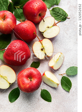 Fresh red apples with green leaves on grey background Fresh red apples with green leaves on grey background 132052032