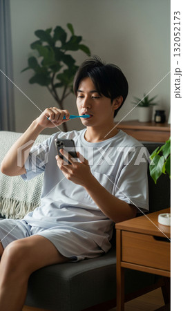 朝。ソファに座り、スマホを見ながら歯磨き 132052173