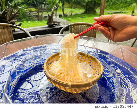 日本の流しそうめん。そうめんを箸で持ち上げてる様子。夏の風物詩。 132053447