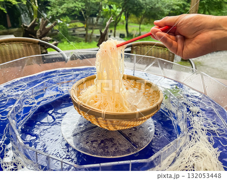 日本の流しそうめん。そうめんを箸で持ち上げてる様子。夏の風物詩。 132053448