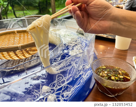 日本の流しそうめん。回転しているそうめんを箸で取っている様子。夏の風物詩。 132053452