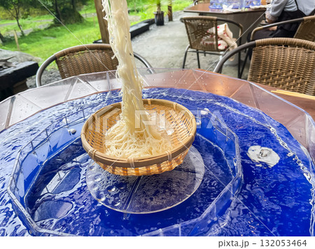 日本の流しそうめん。そうめんを箸で持ち上げてる様子。夏の風物詩。 132053464