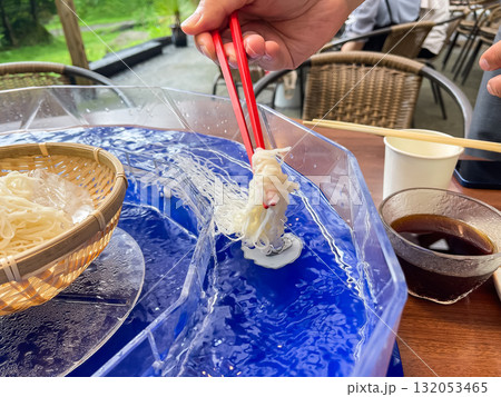 日本の流しそうめん。そうめんを回っている水に入れる様子。夏の風物詩。 132053465