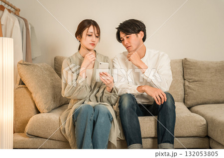 ソファーでスマホを見て驚くショックを受ける夫婦,カップル 132053805