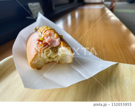 トマトケチャップとマスタードソースをトッピングしたジューシーなホットドッグ。食べている途中。 132053955