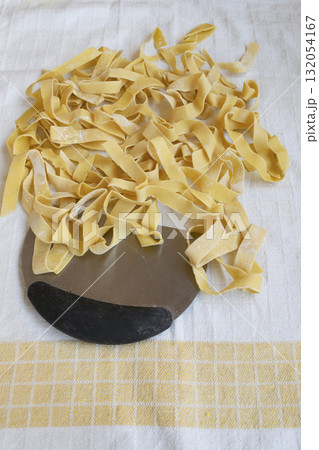 fresh homemade fettuccine pasta on a white cloth with metal cutter fresh homemade fettuccine pasta on a white cloth with metal cutter 132054167