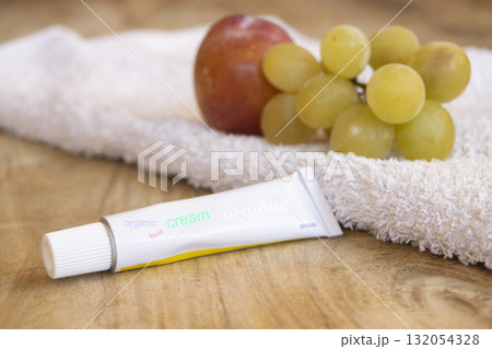 organic face cream tube with fresh fruits and towel on wooden background 132054328