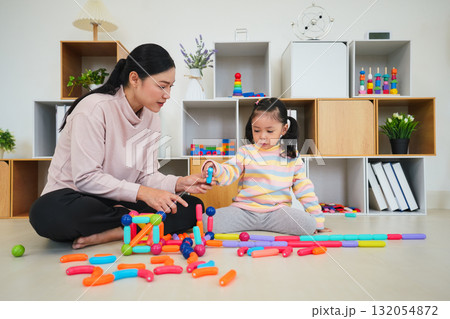 toddler girl and mother playing colorful magnetic construction toy at home 132054872
