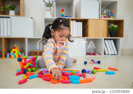 toddler girl playing colorful magnetic construction toy 132054880