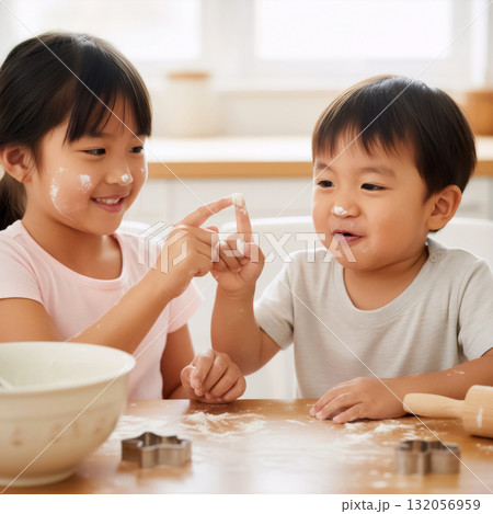 happy asian brother and sister with flour on their faces are baking in the kitchen and playing 132056959