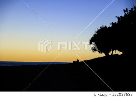 夕暮れの海に沈む夕日と大きな木のシルエット 132057658