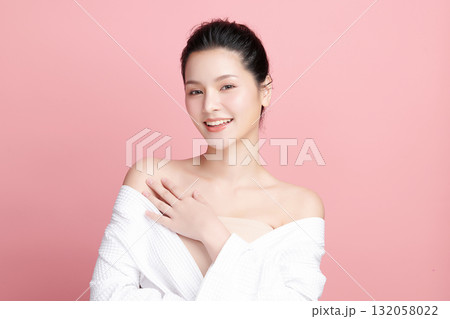 A beautiful young Asian woman with clean, fresh skin against a pink background. Skincare, facial treatment, cosmetology, beauty, and spa. An elegant portrait of an Asian woman. 132058022