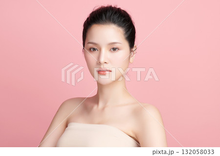 A beautiful young Asian woman with clean, fresh skin against a pink background. Skincare, facial treatment, cosmetology, beauty, and spa. An elegant portrait of an Asian woman. 132058033