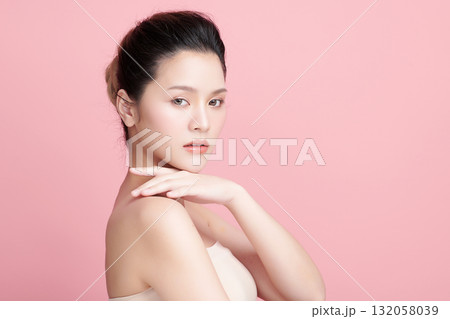 A beautiful young Asian woman with clean, fresh skin against a pink background. Skincare, facial treatment, cosmetology, beauty, and spa. An elegant portrait of an Asian woman. 132058039