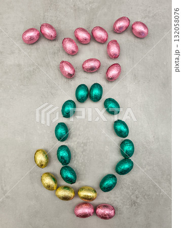 Chocolate easter eggs forming a rabbit shape on a textured surface Chocolate easter eggs forming a rabbit shape on a textured surface 132058076