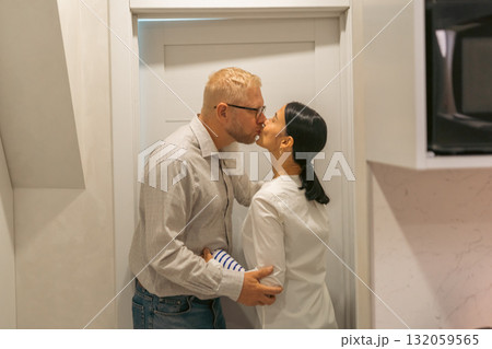 Couple Kissing Kitchen Doorway Romance: Affectionate couple embraces passionately near kitchen doorway, showcasing intimate moment; likely a romantic scene. Couple Kissing Kitchen Doorway Romance: Affectionate couple embraces passionately near kitchen doorway, showcasing intimate moment; likely a romantic scene. 132059565