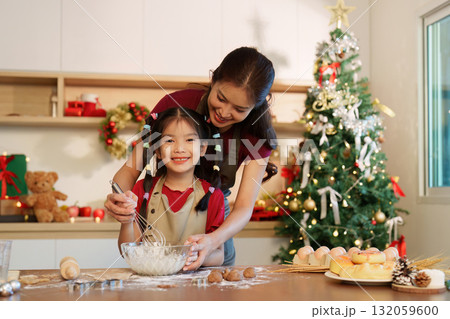 Holiday Baking Fun. Mother and daughter making festive treats together in a cozy kitchen. 132059600