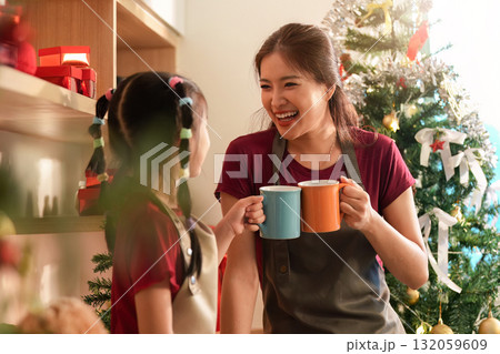 Festive Bonding. Mother and daughter laughing with mugs in cozy holiday kitchen. Festive Bonding. Mother and daughter laughing with mugs in cozy holiday kitchen. 132059609