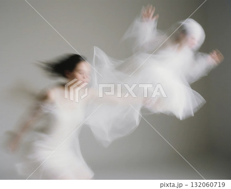 A figure in a flowing white dress appears to be releasing another apparition, creating a captivating scene of playful spirits dancing in a softly lit environment Generative AI 132060719