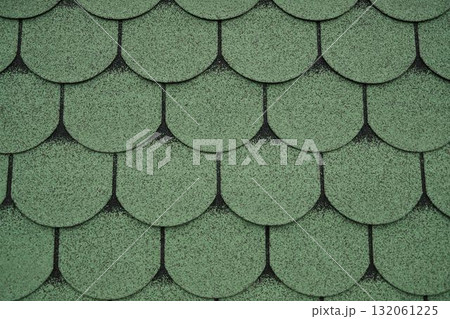 Close up of green asphalt roof shingles forming a pattern. Ideal for construction, architecture, background, or roofing design projects 132061225