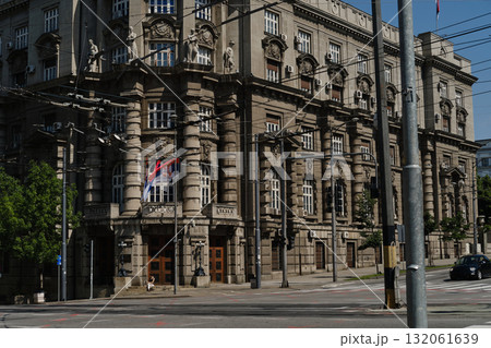 Historic government building in Belgrade with Serbian flag on facade and ornate architecture. Woman traveling with her red merle Border Collie puppy, posing on city street Historic government building in Belgrade with Serbian flag on facade and ornate architecture. Woman traveling with her red merle Border Collie puppy, posing on city street 132061639