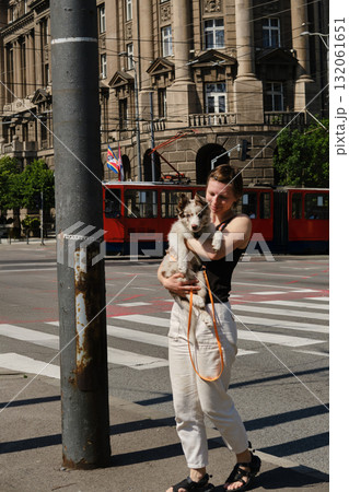 Young woman holding red merle Border Collie puppy on the street in Belgrade with old historic building behind. Travel with pet concept Young woman holding red merle Border Collie puppy on the street in Belgrade with old historic building behind. Travel with pet concept 132061651
