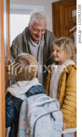Grandfather joyfully interacting with children as they prepare to go outside, showcasing warmth and multigenerational family connections 132062188