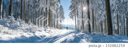 Snowy forest trail with a lone skier enjoying the serene winter landscape, capturing the essence of winter traditions and cozy lifestyle Snowy forest trail with a lone skier enjoying the serene winter landscape, capturing the essence of winter traditions and cozy lifestyle 132062259