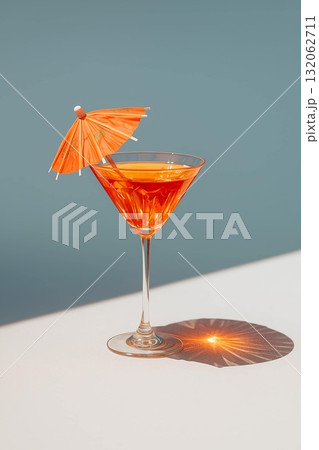 Vibrant cocktail with orange umbrella garnished in elegant glass on minimalistic background 132062711